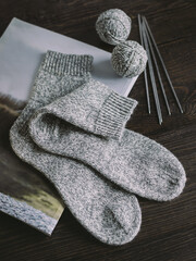 Fototapeta na wymiar Hand knitting socks with needles and yarn balls on a dark wooden background. Concept for handmade and hygge slow life.