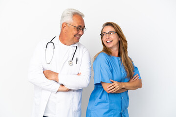 Middle age doctor and nurse isolated on white background looking over the shoulder with a smile