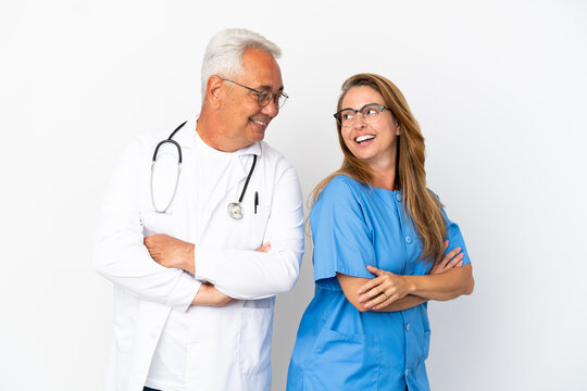 Middle Age Doctor And Nurse Isolated On White Background Looking Over The Shoulder With A Smile