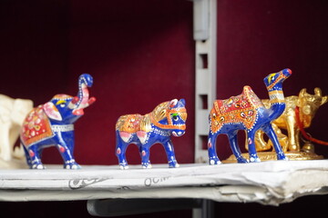 Blue coloured Elephant, camel, horse figurines displayed for sale in a shop. Various Traditional local handicraft. Selective focus.