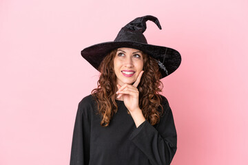 Fototapeta premium Young caucasian woman celebrating halloween isolated on pink background thinking an idea while looking up