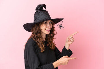 Young caucasian woman celebrating halloween isolated on pink background pointing finger to the side and presenting a product