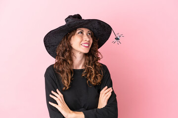 Young caucasian woman celebrating halloween isolated on pink background looking up while smiling