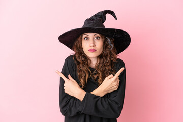 Young caucasian woman celebrating halloween isolated on pink background pointing to the laterals having doubts