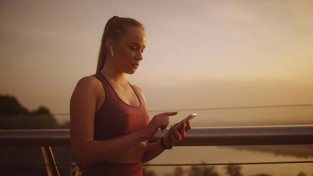 Confident sports woman turning on music on smartphone and going for a run