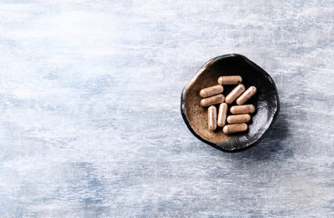 Ashwagandha (Withania somnifera) capsules. Bright wooden background. Top view. Close up. Copy space. 	