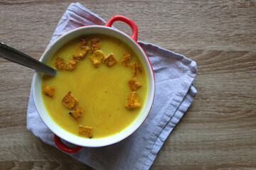 Bowl of vegan pumpkin and tofu curry soup on wooden table. Flat lay.