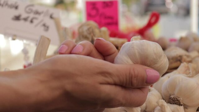 A person picking up garlic in a market