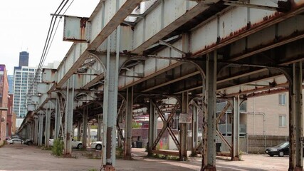 Next to rusted and dirty elevated train tracks in Chicago's south side. Train passes by.