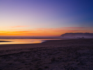 Beautiful landscape. Dust. Sandy ocean shore. The dramatic sky is colored by the orange rays of the setting sun. Tourist place, romance, rest, relaxation. There are no people in the photo..
