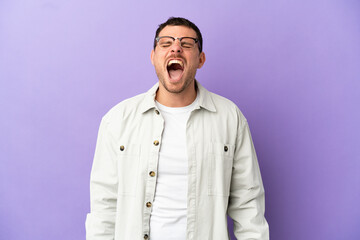 Brazilian man over isolated purple background shouting to the front with mouth wide open