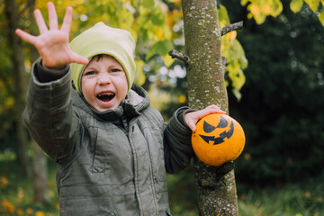 A boy with a Halloween pumpkin with eyes . The feast of fear. Halloween. An orange pumpkin with eyes.