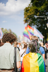 couple covered with lgbt flag in a crowd of people
