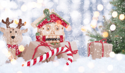 christmas presents with wooden noel, lollipop, nutcracker and christmas tree in the snow with bokeh