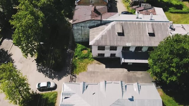 smooth flight on a drone over the gray roofs of small concrete houses, summer, green trees, asphalt roads, in some places there are cars