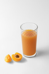 slices of fresh orange apricot and glass with citrus juice isolated on a white and gray background...