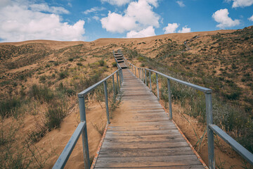 Obraz premium wooden walkway bridge under sand in dunes in Dagestan