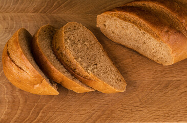 part of a loaf of bread and slices cut from it, laid on a wooden board, view from the top