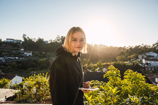 blonde woman with the mobile on a gazebo against sunset
