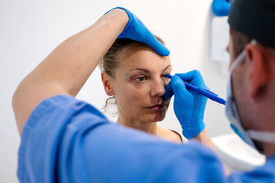 Surgeon drawing line on girl eye with marker preparing for procedure.