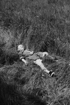 Happy boy lies on the grass in a summer park. Cute positive kid