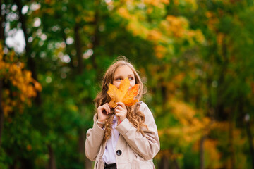 Adorable little girl with autumn leaves in the beauty park