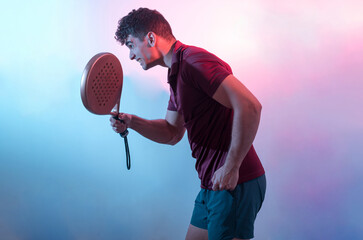
a young man posing in a bicolor background with a paddle racket.
paddle sport.