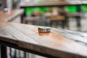Selective focus of an ashtray on a narrow wooden bar table