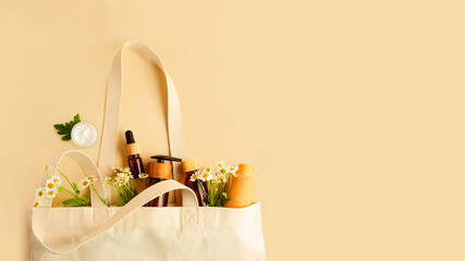 Open eco friendly cotton reusable bag with the different wooden and glass containers.Fresh chamomile in it.Concept of organic,zero waste cosmetics.Woman bag with accessories.Large banner.