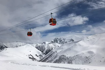Papier Peint photo Gondoles Two red gondolas on sky and cloudly background lift people in high mountains. Active winter leasure concept.
