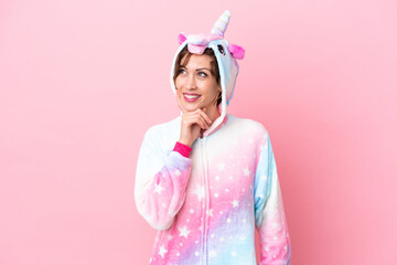 Young caucasian woman with unicorn pajamas isolated on pink background thinking an idea while...