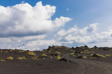 Volcanic-lunar landscape in Kamchatka, rocks from volcanic rocks against the background of a blue sky with clouds. Klyuchevskaya group of volcanoes.