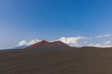 Volcanic-lunar landscape in Kamchatka, rocks from volcanic rocks against the background of a blue sky with clouds. Klyuchevskaya group of volcanoes.