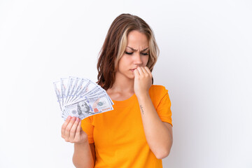 Young Russian girl holding dollars isolated on white background having doubts