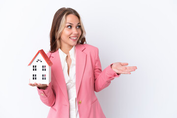 Real estate Russian agent holding a toy house isolated on white background with surprise expression...