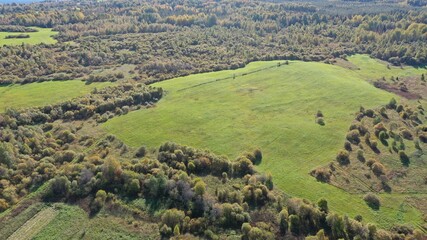 Fields in the middle of the forest. Hayfields. Autumn landscape with green fields. Top view and aerial photography of the fields.