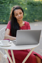 beautiful and young millennial african woman in a public place working on a laptop. african american businesswoman working in a park or doing online teaching. watching a webinar or creating content