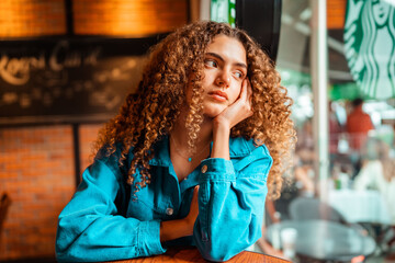 curly haired girl sitting and looking through the window