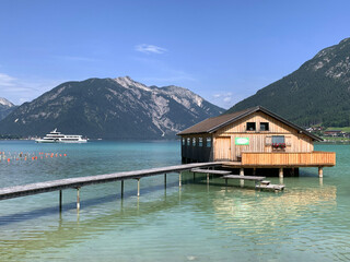 The wooden floating house and the ferry on the emerald Achensee