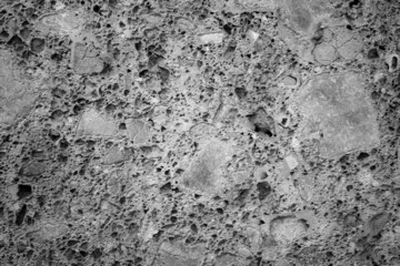 evocative black and white image of very porous concrete wall
