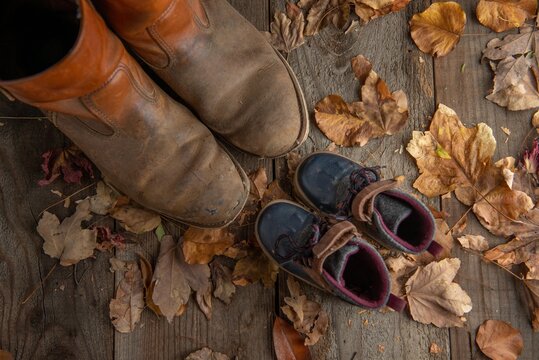 Boots and child boots on wooden floor with fall leaves