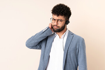 Telemarketer Moroccan man working with a headset isolated on beige background having doubts