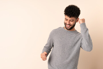 Young Moroccan man isolated on beige background celebrating a victory