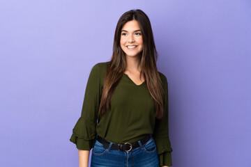 Fototapeta premium Teenager Brazilian girl over isolated purple background looking to the side and smiling