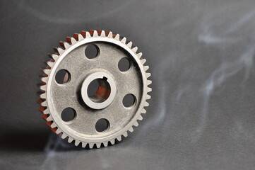 Engine parts. Metal cogwheel on a dark background. Spare parts.