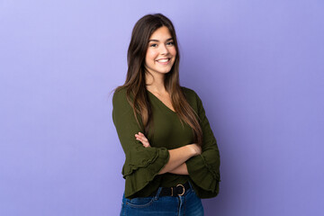 Teenager Brazilian girl over isolated purple background with arms crossed and looking forward