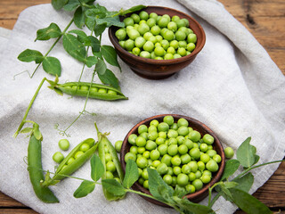 Fresh green peas young in bowl, on wood table, top view, seeds, pods, sprouts.