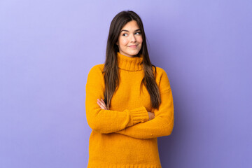 Teenager Brazilian girl over isolated purple background having doubts while looking side