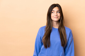 Fototapeta premium Teenager Brazilian girl over isolated background having doubts while looking side