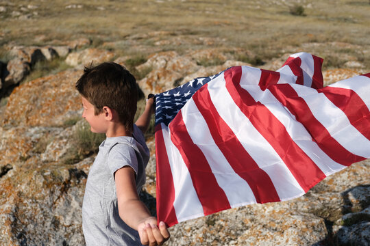 A boy holding waving US flag, beeng a patriot concept